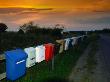 A Row Of Colourful Mailboxes On A Fence By A Gravel Road by Christian Lagerek Limited Edition Pricing Art Print