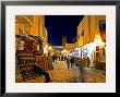 People Strolling Along Cobblestone Street Past Carpet Seller At Twilight, Kairouan, Tunisia by Bethune Carmichael Limited Edition Pricing Art Print