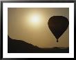 A Hot Air Balloon Rises Above A Hilly Landscape At Sunrise by Raul Touzon Limited Edition Print