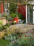 View To The Patio With Metal Table And Chairs, Red Walls And Angled Drystone Walling by Clive Nichols Limited Edition Pricing Art Print