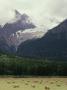 Glacier Descending From Clouded Mountains Contrasts With A Field Dotted With Rolls Of Hay by Sylvia Sharnoff Limited Edition Print