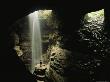 Caver Stands In A Beam Of Sunlight In Front Of A Waterfall by Stephen Alvarez Limited Edition Print