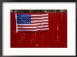 A United States Flag Hangs On A Bright Red Fence by Raul Touzon Limited Edition Print
