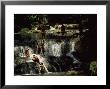 Gently Sloping Waterfalls Surrounded By Rich Vegetation In Which Eight Novice Monks Are Bathing by James L. Stanfield Limited Edition Pricing Art Print