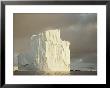 Twilight View Of A Large Iceberg Under A Cloudy Sky by Bill Curtsinger Limited Edition Print