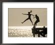 Silhouette Of Girls Jumping Off Pier by Anne Flinn Powell Limited Edition Pricing Art Print
