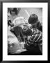 Girl Demurely Adjusting Her Hair While Willing Volunteers Repair Jammed Front Wheels Of Her Car by Nina Leen Limited Edition Print