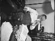 Writer Damon Runyon Sitting With Feet Up At Work-Piled Desk Drinking Milk by Gjon Mili Limited Edition Print