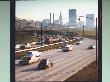 Traffic On Curving Stretch Of Highway With Skyscrapers In Distance by Ralph Crane Limited Edition Print