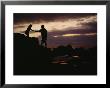 A Man With A Camera Helps A Woman Down Rocks Near Tanah Lot Temple by Eightfish Limited Edition Print