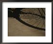 A Bicycle Wheel Casts A Shadow On A Wall And Sidewalk In Siena by Raul Touzon Limited Edition Print
