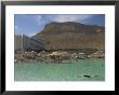 People Floating In The Sea And Hyatt Hotel And Desert Cliffs In Background, Dead Sea, Middle East by Eitan Simanor Limited Edition Print