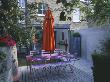 Small Courtyard Garden With Pink Wooden Table, Orange Parasol, Decking And Orange Cannas by Clive Nichols Limited Edition Print