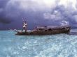 Bajau Fisherman In Traditional Lepa Boat With Rain Clouds Behind, Pulau Gaya, Borneo, Malaysia by Jurgen Freund Limited Edition Print