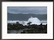 Waves Crashing Upon Rocks With Mountains In Background On Cloudy Day by Todd Gipstein Limited Edition Print
