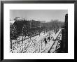 Woman Sweeps Snow Off A Snow-Covered Street Lined With Brownstones Near Two Horse-Drawn Buggies. by George B. Brainerd Limited Edition Print