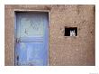 Next To A Blue Door, A Cat Peers Out Of The Window Of An Adobe House by Ira Block Limited Edition Print