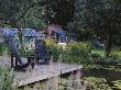 View Over Lily Pool To Wooden Deck With Adirondack Chairs, Designer: Duncan Heather by Clive Nichols Limited Edition Print