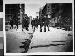 Rear View Of A Group Of Men In Uniform, Wearing Riding Boots And Walking Down A City Street by Wallace G. Levison Limited Edition Print