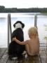 Rear View Of A Child Sitting With A Dog On A Pier, Sweden by Berndt-Joel Gunnarsson Limited Edition Print