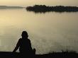 Silhouette Of A Woman Sitting At The Lakeside, Lake Malaren, Sweden by Ewa Lundgren Limited Edition Print